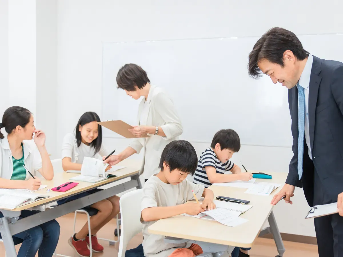 学習塾で小学生に勉強を教えるアジア人塾講師・先生（夏期講習）
